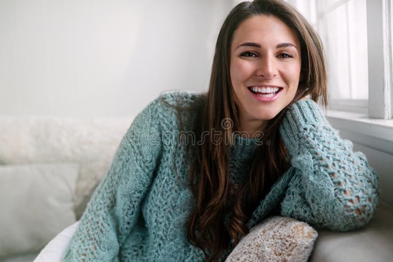 Casual pretty female sitting relaxed at home on sofa, perfect smile, straight white teeth portrait.