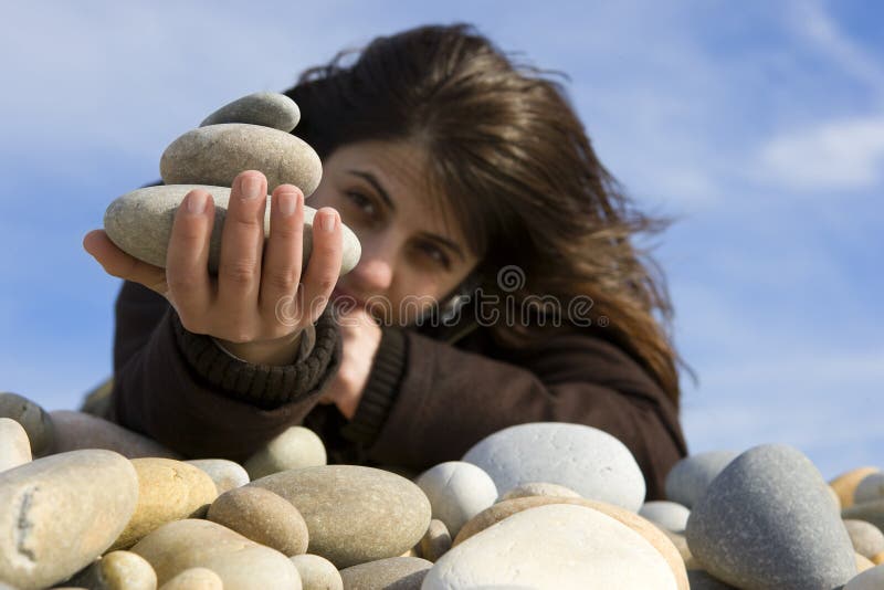 Casual woman holding stones in the beach