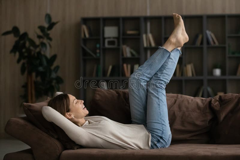 Giving rest to feet. Young casual lady relax on sofa barefoot. Selective  focus on well groomed