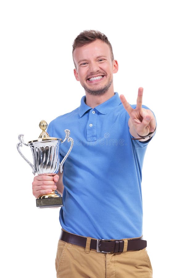 Casual young man with trophy shows victory sign