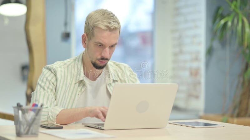 Casual Young Man typing auf Laptop stockbild
