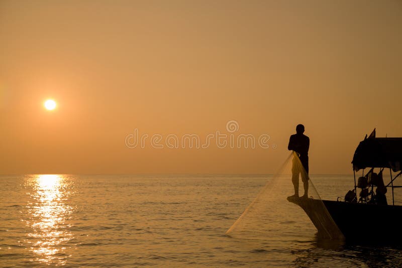 The fisherman catches fish with net by the sea at sunrise. The fisherman catches fish with net by the sea at sunrise