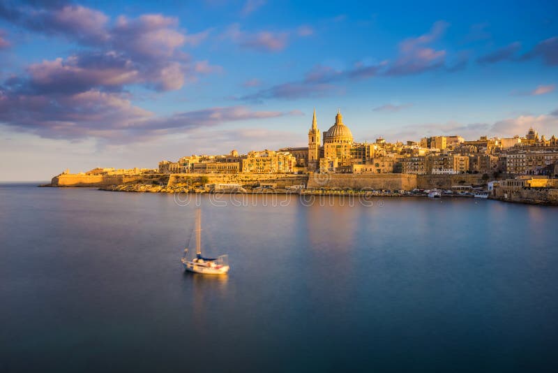 Catedral do ` s de Valletta, Malta - de StPaul na hora dourada no capital Valletta do ` s de Malta com veleiro fotografia de stock Catedral do ` s de Valletta, Malta - de StPaul na hora dourada no capital Valletta do ` s de Malta com veleiro fotografia de stock