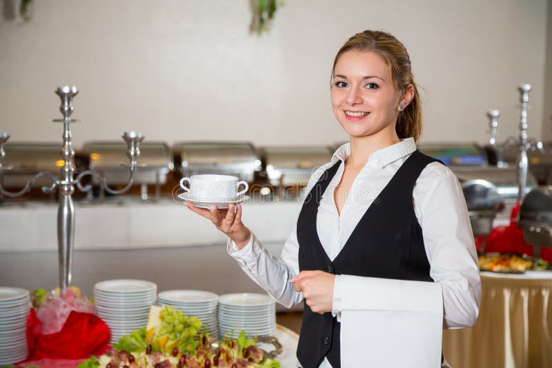 Catering service employee in restaurant posing with soup dish