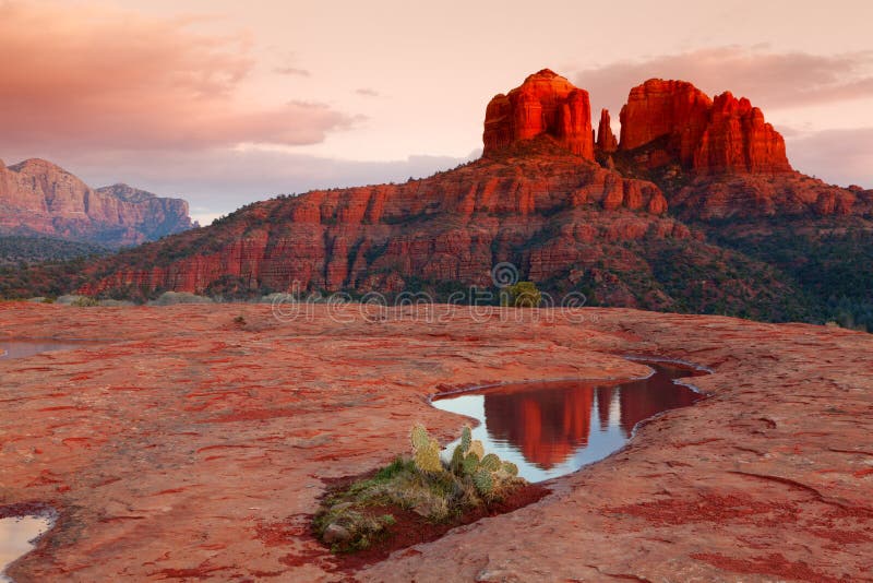 Cathedral Rock in the distance is reflected in a pool of water at sunset. Cathedral Rock in the distance is reflected in a pool of water at sunset