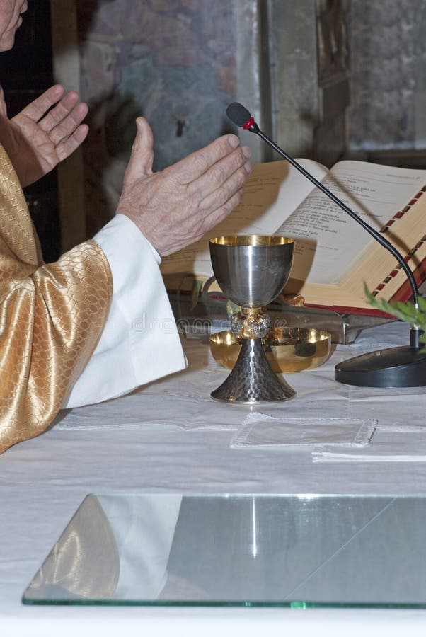 Catholic priest with chalice and bible during catholic mass