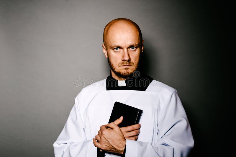 Catholic priest in white surplice holding bible stock photography Catholic priest in white surplice holding bible stock photography
