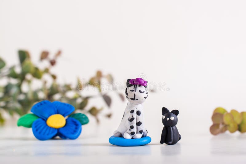 Cats and a flower made of polymer clay on a light background. Handmade decor.