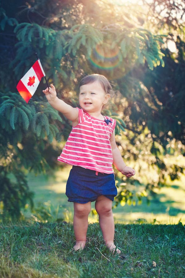 Caucasian baby girl holding Canadian flag with red maple leaf