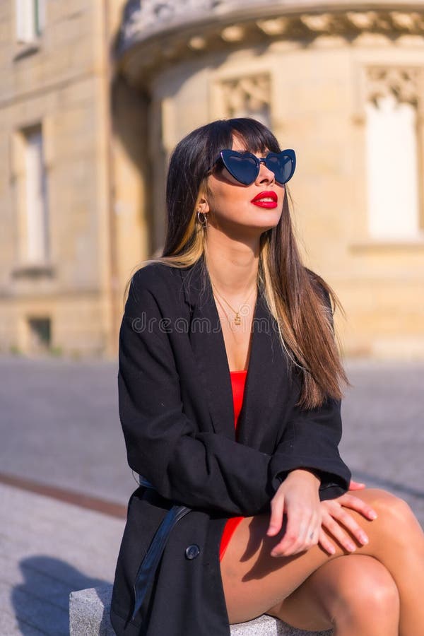 Caucasian Brunette Girl Wearing Red Dress And Glasses Posing In Front Of Arbide Tower Stock