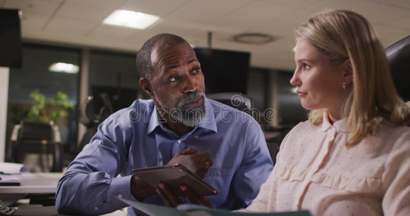 Professional businessman and businesswoman discussing over a digital tablet in modern office in slow stock footage