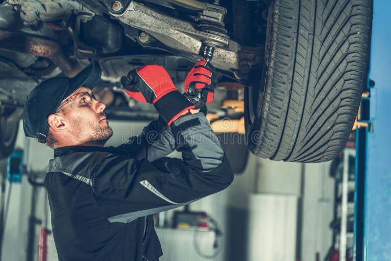 Caucasian Car Mechanic Adjusting Tension in Vehicle Suspension Element. Professional Automotive Service. Caucasian Car Mechanic Adjusting Tension in Vehicle Suspension Element. Professional Automotive Service.