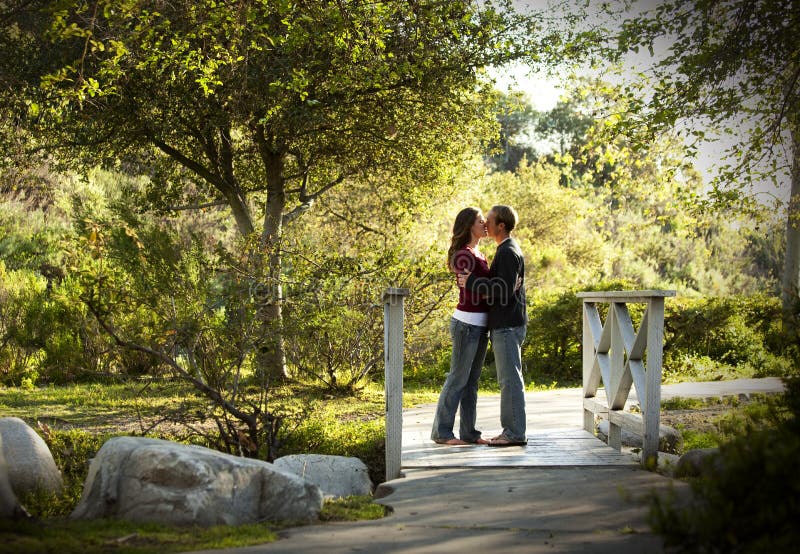 Caucasian couple kissing on outdoor wooden bridge