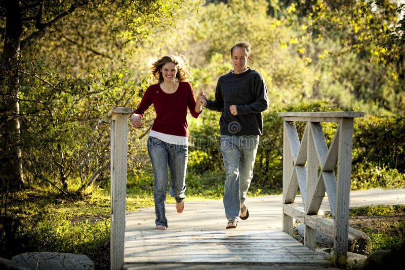 Caucasian couple running on bridge holding hands