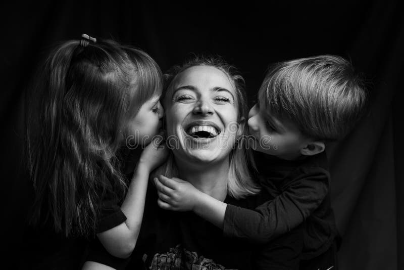 Caucasian Family Portrait in Black and White. mom daughter and son. mom laugh. son and daughter kiss mom on the cheeks