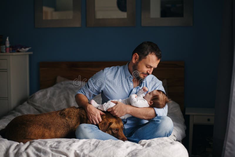 Caucasian father with newborn baby. Dog pet laying on bed. stock image Caucasian father with newborn baby. Dog pet laying on bed. stock image