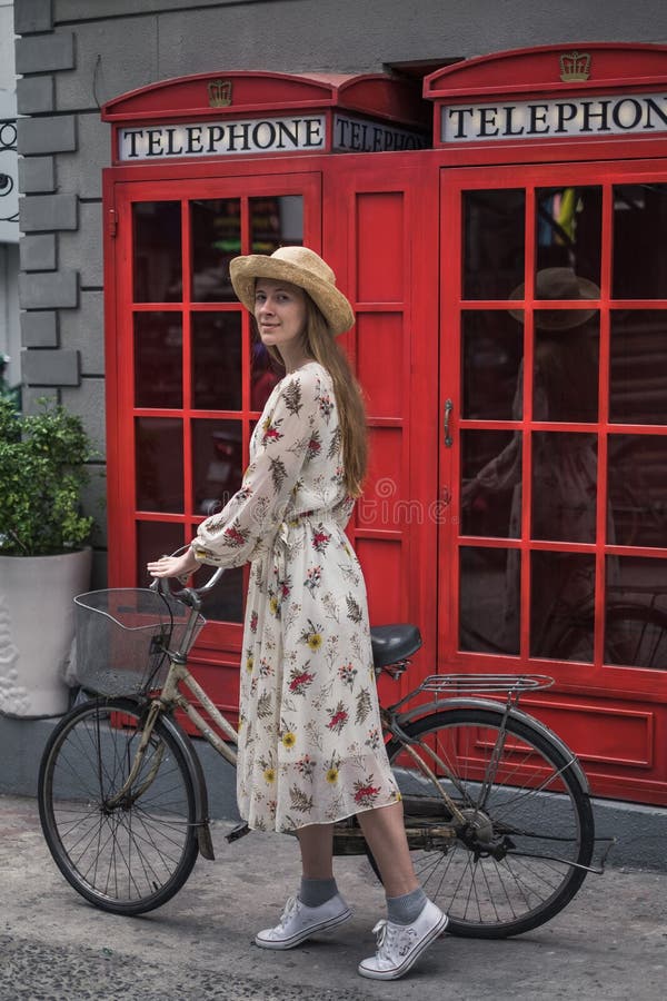 Caucasian hipster girl in dress, sneakers and straw hat standing