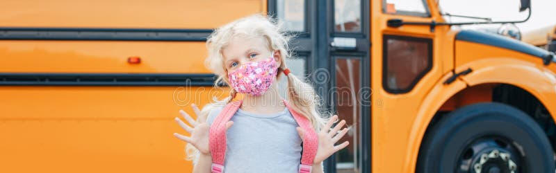 Caucasian girl kid student in face mask standing by the yellow school bus. Education system and back to school in September. New royalty free stock images Caucasian girl kid student in face mask standing by the yellow school bus. Education system and back to school in September. New royalty free stock images