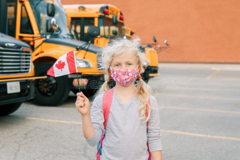 Caucasian girl student in protective face mask with Canadian flag. Student kid near yellow school bus outdoor. Education and back stock images Caucasian girl student in protective face mask with Canadian flag. Student kid near yellow school bus outdoor. Education and back stock images