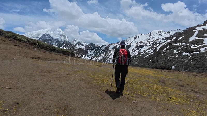 Caucasian hiker walking towards snowy mountain under cloudy sky in Yunnan Province, China stock video