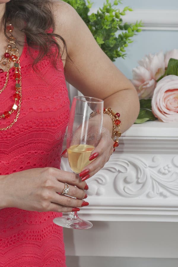 Caucasian kvinna i den röda klänningen som rymmer ett exponeringsglas av champagnecloseu