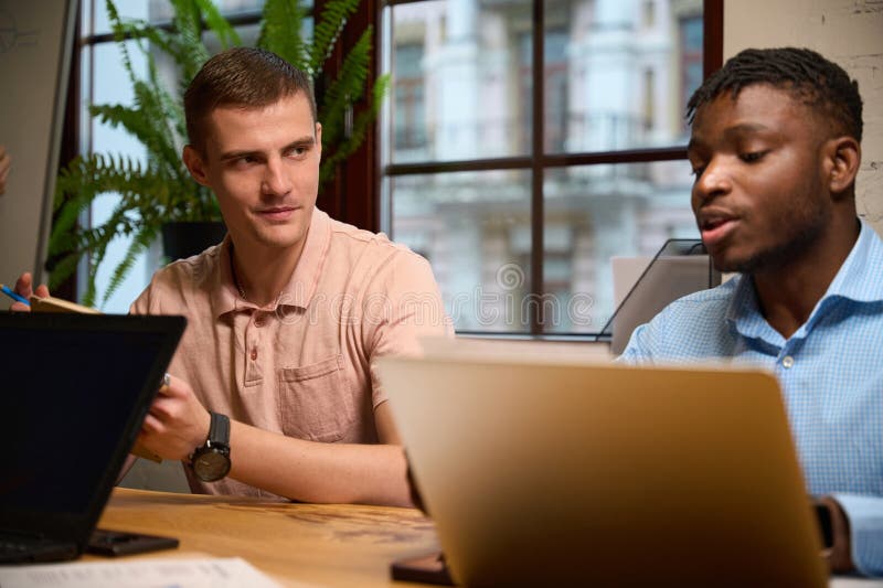 Bărbat caucazian ascultând cu atenție colegul său american african royalty free stock photography