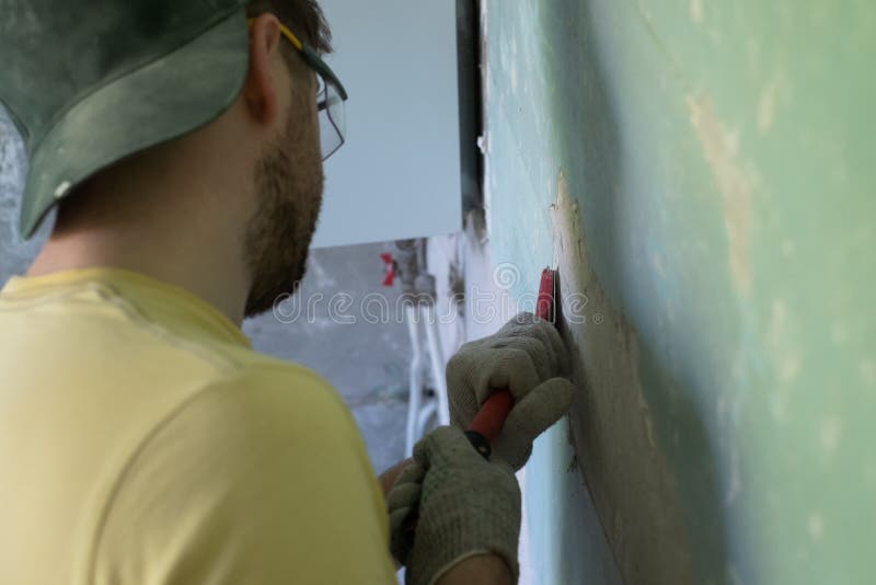 Caucasian Man Removing Old Paint with Scraper Tool. Stock Photo Image