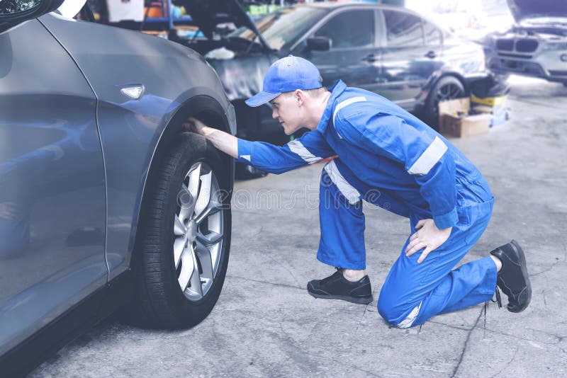 Caucasian Mechanic Checking on a Tyre in a Stock Image Image