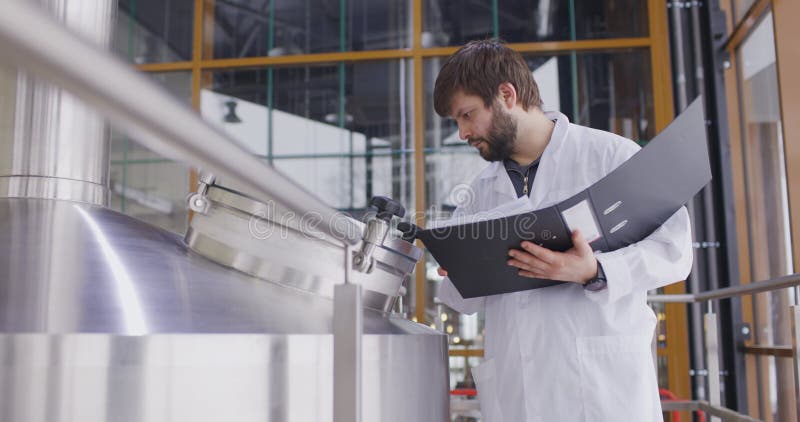 Caucasian Men working at brewery or beer factory. Men With Tablet near the Beer Tanks