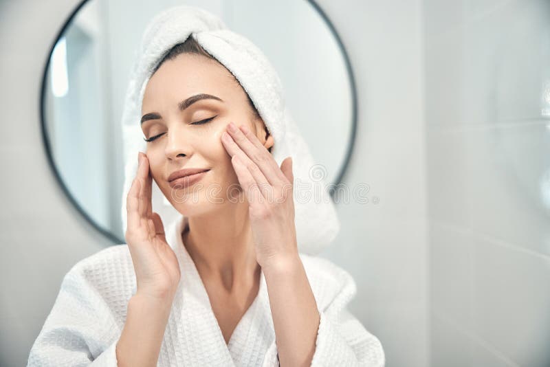 Caucasian Pretty Woman Doing Relaxing Face Massage In Bathroom Stock