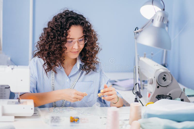 Caucasian Tailor Stretching Thread at Sewing Stock Photo
