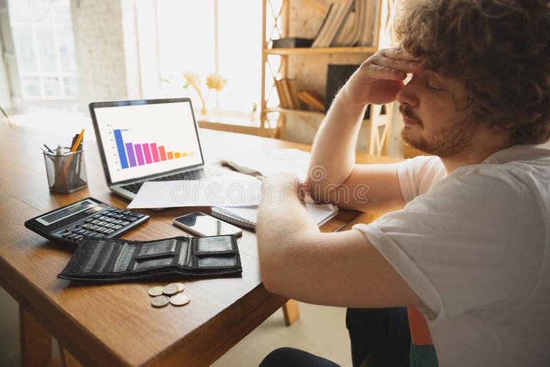 Caucasian upset and despair man watching financial and economical graphs going down during coronavirus quarantine