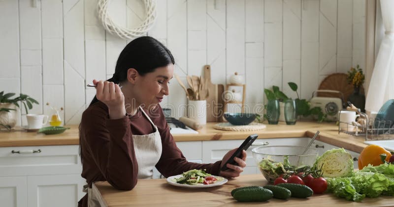 Caucasian Woman Enjoying Salad while Using Phone