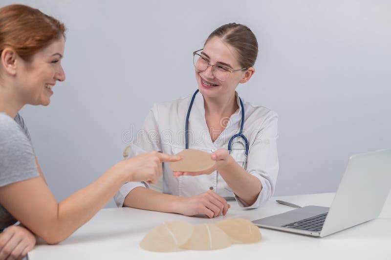 Caucasian Woman and Plastic Surgeon Touching and Choosing Breast Implants. Stock Photo Image