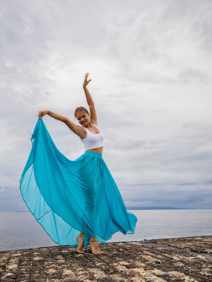 Outdoor yoga practice near the ocean. Young woman practicing Adho Mukha  Vrksasana. Yoga Handstand is an inverted asana. Beautiful asana. Strong  slim body. Yoga retreat. Copy space. Bali Stock Photo