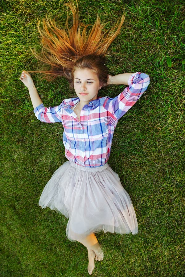 Caucasian woman with red messy hair lying on grass in plaid shirt and tulle tutu skirt. View from above top royalty free stock photos Caucasian woman with red messy hair lying on grass in plaid shirt and tulle tutu skirt. View from above top royalty free stock photos