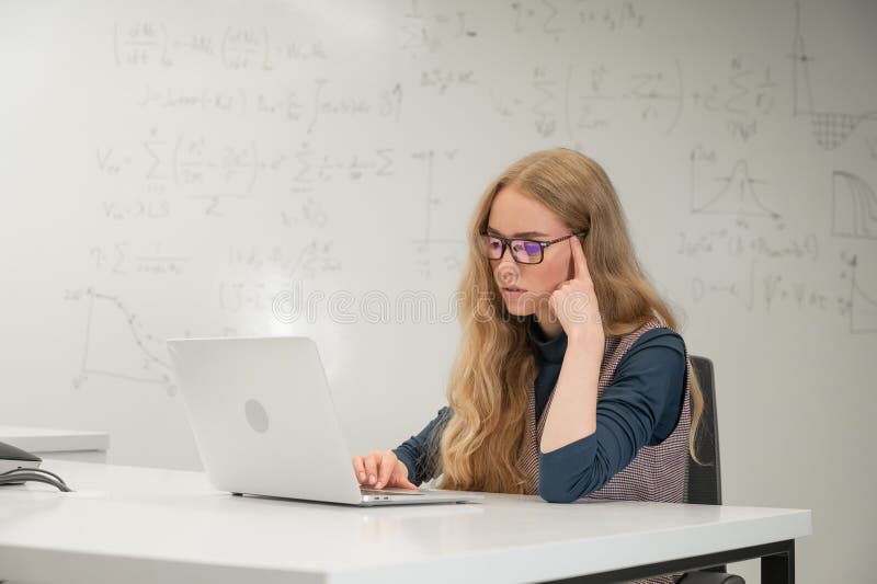 Caucasian woman scientist typing on laptop. White board with formulas. royalty free stock photo