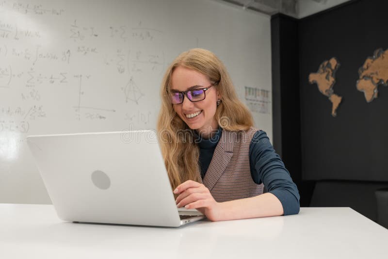 Caucasian woman scientist typing on laptop. White board with formulas. stock image