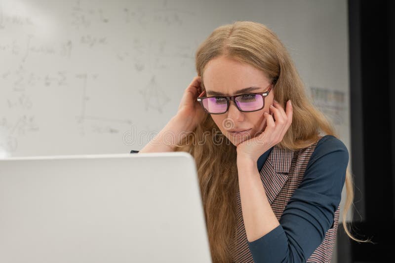 Caucasian woman scientist typing on laptop. White board with formulas. royalty free stock image