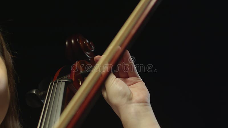 Caucasian woman turns spike on cello with a smooth movement of her hand, then shows bow and continues to twist black stock footage