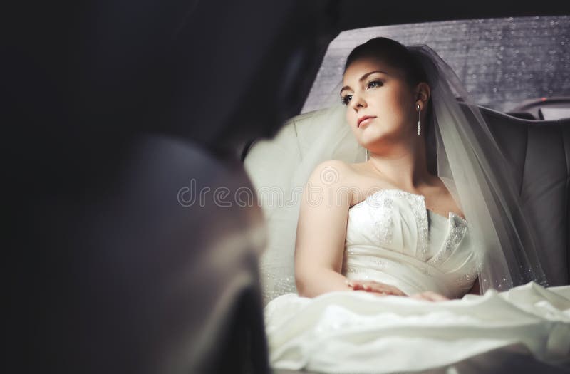 Caucasian young bride sitting in limo. stock photography