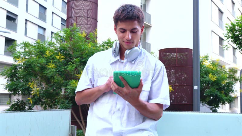 Young man using a tablet outdoors for digital interaction. Vertical stock video
