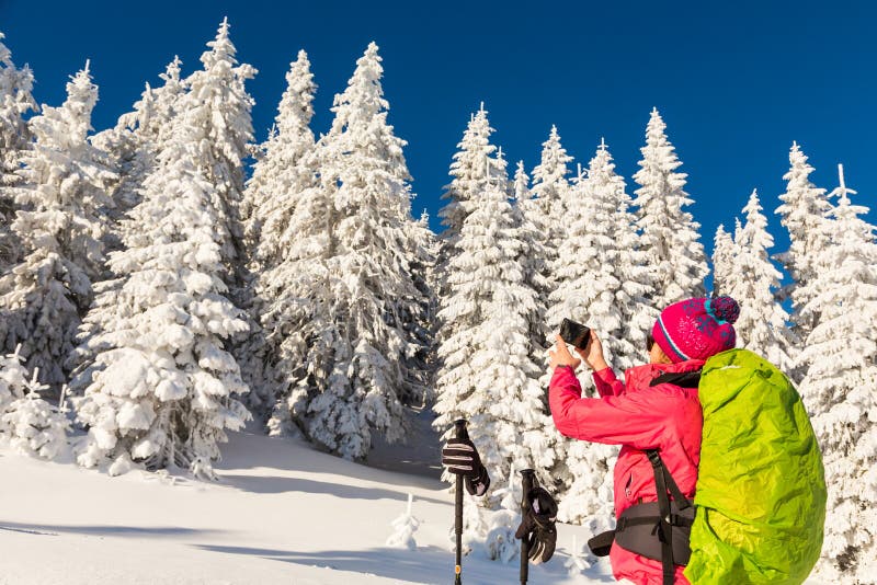 Caucasian young woman in colorful outfit taking a break from backcountry skiing taking a picture, recording the beautiful winter royalty free stock images Caucasian young woman in colorful outfit taking a break from backcountry skiing taking a picture, recording the beautiful winter royalty free stock images