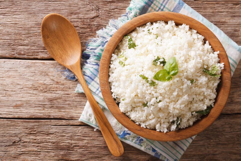 Cauliflower rice with basil close up in a bowl on the table. horizontal top view. Paleo cauliflower stock images, royalty-free photos and pictures