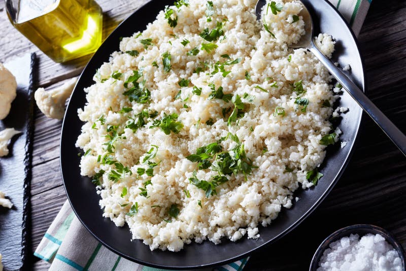 Close-up of Cauliflower rice or couscous mixed with finely chopped parsley in a black bowl on an old rustic table, horizontal view from above. Paleo cauliflower stock images, royalty-free photos and pictures