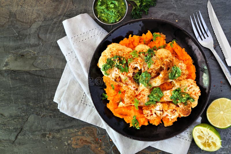 Cauliflower steak with sweet potato mash, top view scene on a slate background