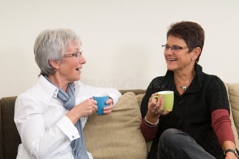 Two senior women drinking coffee, chatting and having a good time together as girl-friends. Two senior women drinking coffee, chatting and having a good time together as girl-friends.