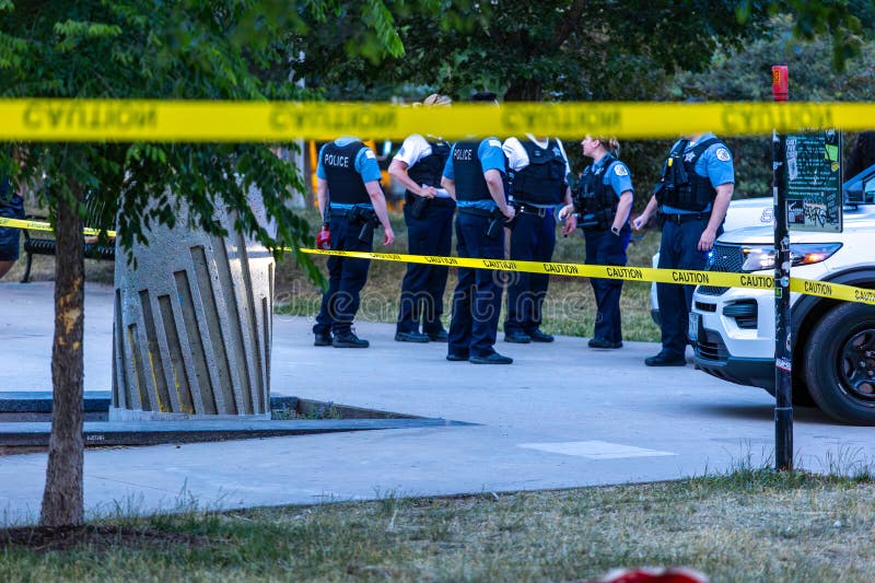 caution tape wrapped around tree blocking access to a crime scene that happen in Chicago during sunset