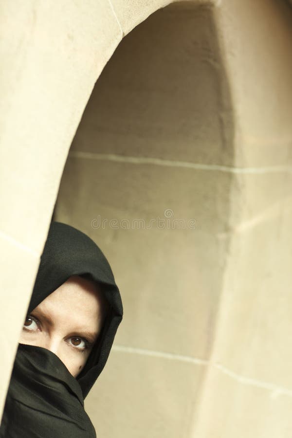 Cautious Islamic Woman in Window Pane Wearing Burqa or Niqab