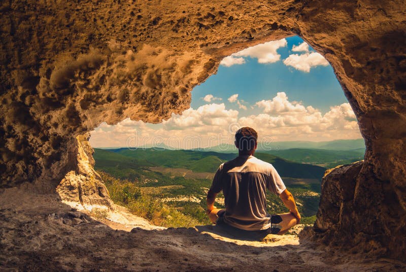 The man who meditates in a cave overlooking the mountain valley. Adventurer adventure stock images, royalty-free photos and pictures